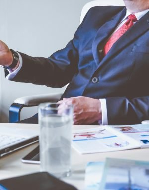 pexels-photo-288477-288477 Professional man gesturing in a business meeting at an office desk, conveying confidence and leadership.